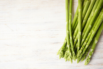 Fresh green asparagus on wooden background, space for text. Flat lay.