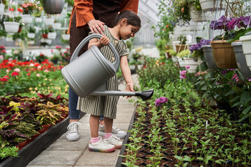 Girl holding watering can and taking care of the plants and flowers