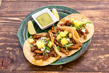 Top view image of delicious Mexican al pastor tacos with lime wedges, corn tortillas and some...