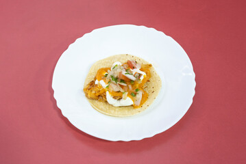Solitary chicken tinga taco with white onion, unrecognizable sauce and wheat tortilla on white plate