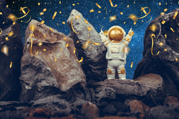 Astronaut standing on rocky mountain celebrating with raising arms while falling shiny golden...