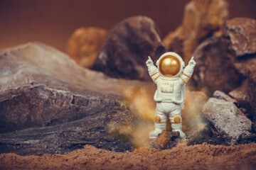 Proud astronaut celebrating with raising arms while standing on rocky mountain.