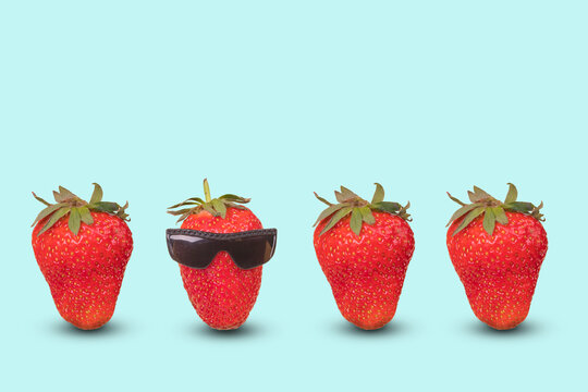 Creative idea with outstanding red strawberry with goggles and fresh ripe strawberries on pastel blue background.