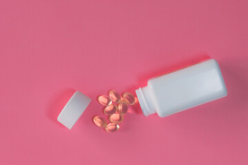 white bottle of transaprene medicine pills scattered on a pink table health concept