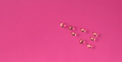 set of transparent medicine capsules scattered on pink background health care concept