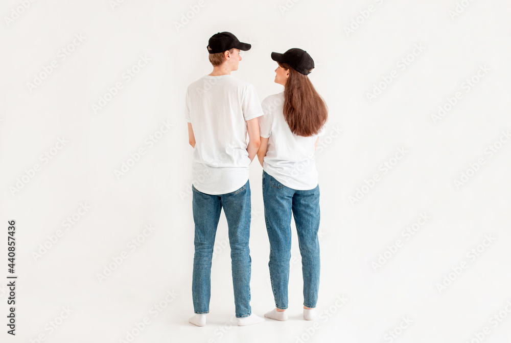 Wall mural A man and a woman in white T-shirts are standing backwards. Next to a friend on a white isolated background