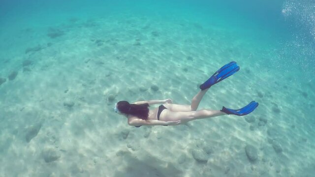 Girl going underwater with mask and flippers. Young girl diving into the crystal clear blue sea water. Swimming in an unbelievable transparent turquoise sea.