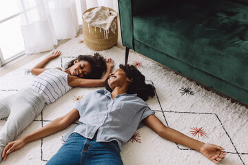 Mother and daughter pretending to be asleep on floor - Powered by Adobe