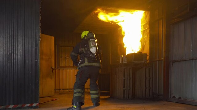 A firefighter or fireman with uniform using water fire hose against hot burning fire and dangerous smoke in the container, an emergency accident rescue. People. Hero