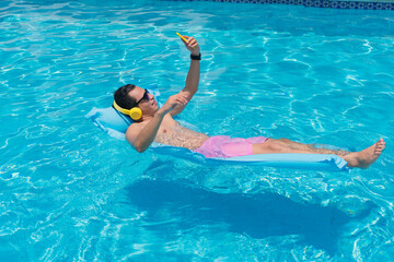 Young Latino man at the pool using his cell phone.