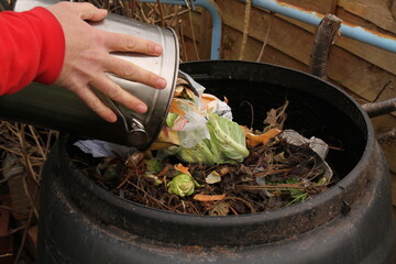 Emptying the contents of a kitchen compost bin into an outdoor compost bin,  to produce...