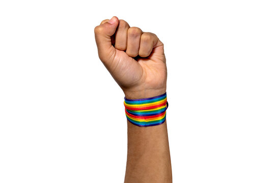 Raised fist of a person wearing a rainbow bracelet. Symbol of the LGBTQIA+ community. Concepts of fight against prejudice. Isolated, white background