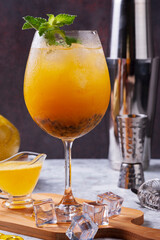 passion fruit cocktail  on a kitchen board with some ice cubes on the floor,  whole passion fruit, cocktail shaker, strainer and doser. Copy space
