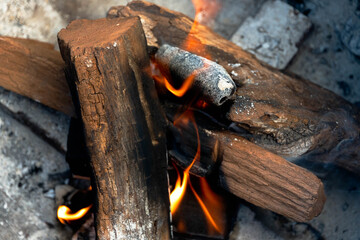 Photo of a fire pit and fire consisting of mesquite dried-wood logs and fruit wood charcoal on a...