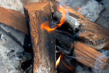 Photo of a fire pit and fire consisting of mesquite dried-wood logs and fruit wood charcoal on a sunny day of June 20, 2021.