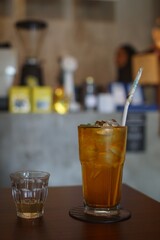 Focus of choice from a glass of black iced tea with liquid sugar on the side