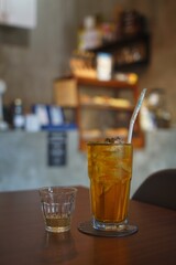 Focus of choice from a glass of black iced tea with liquid sugar on the side
