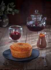 homemade cake, rustic wooden table, blurred background with a teapot of tea and a glass