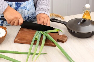 Asian Female Hand Cutting Green Spring Onion using Black Knife on Wooden Chopping Board, Cooking...