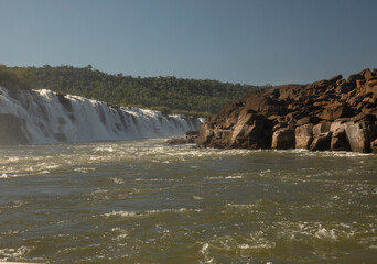 Sailing the river. The majestic Mocona waterfalls seen from the boat. The falling white water, rocks and river flowing across the jungle.