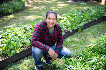 Asian man farmer sitting and smile in organic vegetable garden