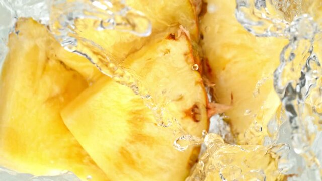 Super Slow Motion Shot of Pineapple Slices Falling Into Water Whirl at 1000 fps.