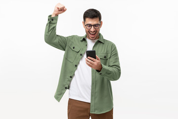 We've got a winner! Happy young man in green shirt looking at phone screen with victory expression, isolated on gray background