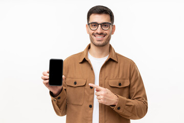 Handsome man in brown shirt presenting smart phone and pointing with finger at blank black screen...
