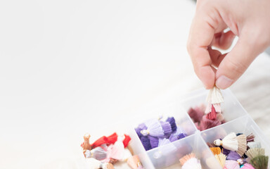 Hand holding multicolor tassel choosing for decorating with many things as earring pendant or decorate with the leather bag, The tassel put on the plastic box.