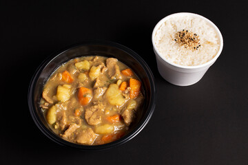meat in sauce with potatoes and carrots in a disposable bowl for delivery