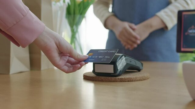 Close-up hand asia woman people work in small sme coffee caf&eacute; shop store owner use cashless wifi paywave nfc scan app smart pos reader sale in take out food drink order in urban city life contactless.