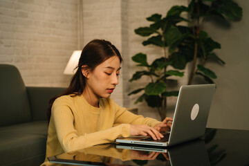 Workaholic and tired young Asian businesswoman working overtime on laptop till late night...
