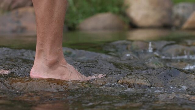 close up hand touching water in the forest river nature and life concept