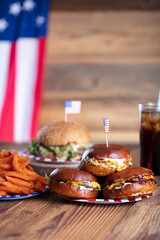 
Fourth of July celebration. American flag and decorations. Burgers on rustic wooden table.
