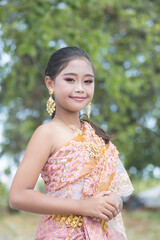 Half-body portrait of an Asian schoolgirl dressed in traditional Thai costumes smiling and looking at the camera.