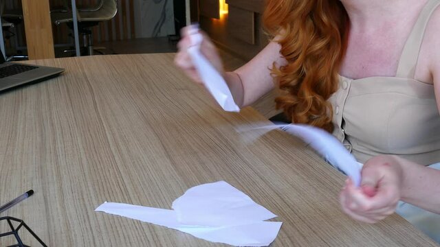 Woman nervously tears the paper into small pieces while sitting in the office.