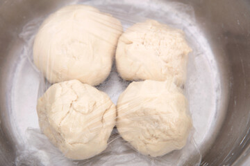 Four large dough pieces in a basin