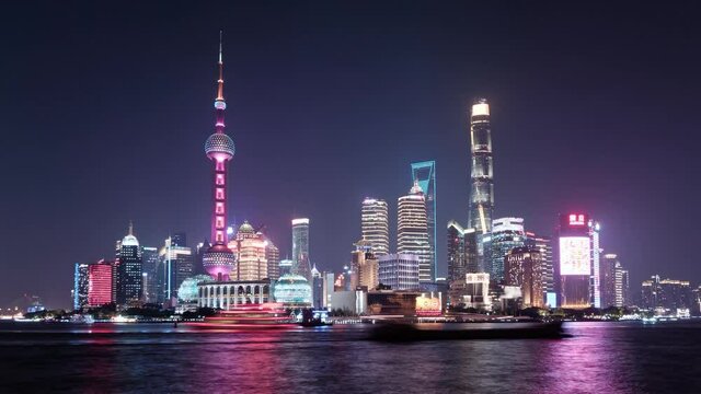 Shanghai skyline viewed from bund at night, skyscrapers and landmarks with ships sailing on Huangpu river, time lapse 4k footage.