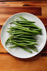 Plate of green beans just picked from the farm on a wood table