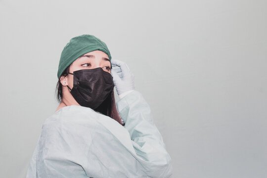 Closeup Of An Attractive Cheerful Female Nurse In A Black Facemask Touching Her Eyebrow