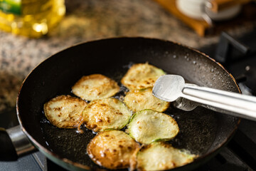 fired zucchini on pan with tongs