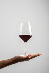 hand supporting full wineglass on white background.