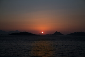 Beautiful twilight orange sunset. Sunset silhouette of horizon above water, over sea and mountains