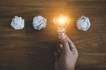 Hand choose light bulb and crumpled office paper. Concept of inspiration creative idea thinking and...