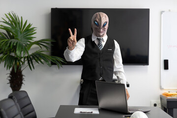 A humanoid Alien in a white shirt, business suit gesturing victory sign and looking at camera in the office, concept of hand sign or makes hands gesture. Selective focus on hand, shows V sign, Peace