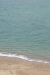 Detail of the turquoise sea with sand on the shore. Vertical photo.