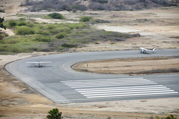 Two airplanes on the runway in the middle of the field.