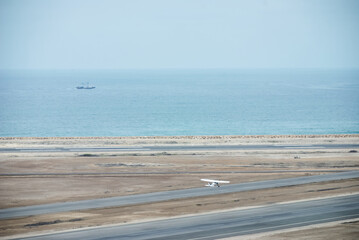 Light aircraft taking off on the runway next to the pacific ocean.