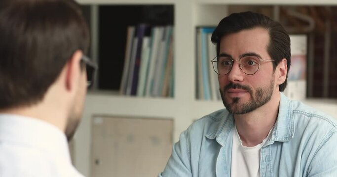 Head shot concentrated young male job seeker passing interview, making good first impression on hr manager. Serious businessman discussing working issues with partner, sharing ideas at meeting.