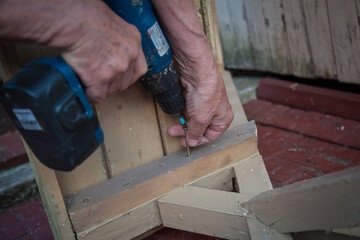 A worker uses a screwdriver to repair wooden furniture.